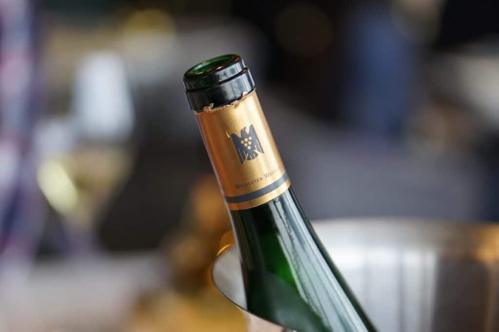 A bottle of red wine chilling in a metal ice bucket — serving light reds at cellar temperature