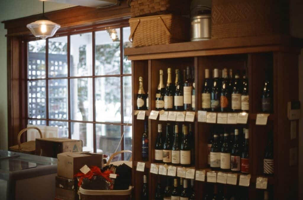 Independent wine shop shelf with European wine bottles and visible price tags in warm lighting
