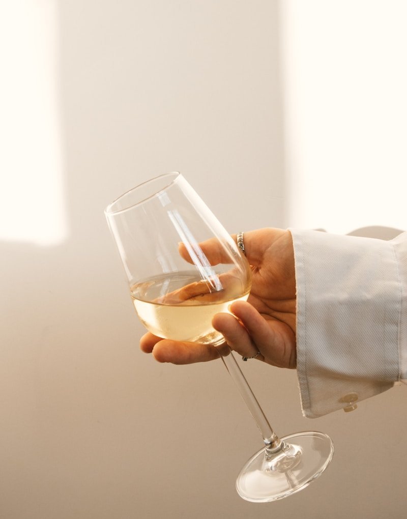 Glass of white wine held delicately, evoking the scarcity and preciousness of white Burgundy